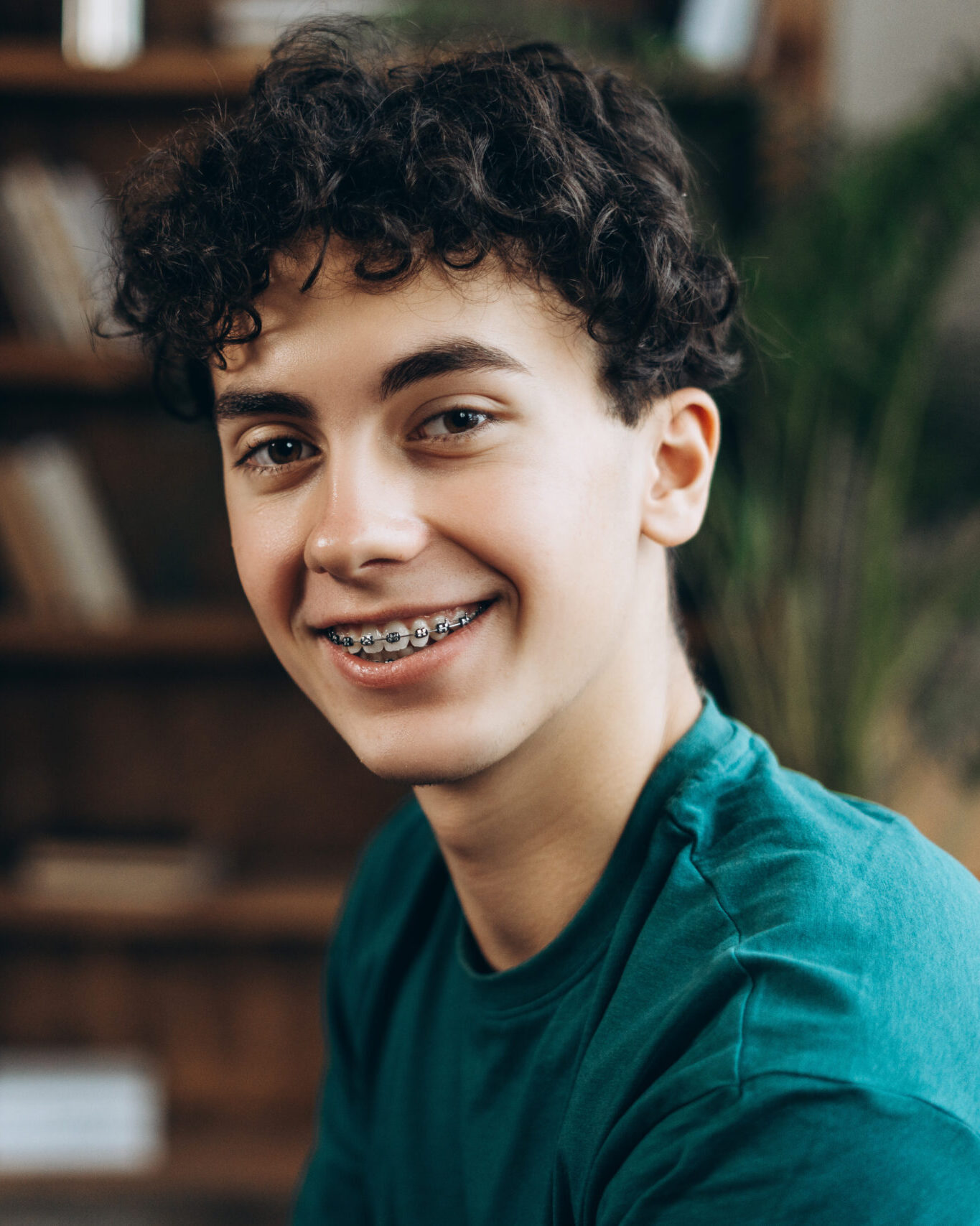 Portrait of smiling teenage boy with braces posing at camera in the office. Fashion model posing looking at camera. Dental care concept