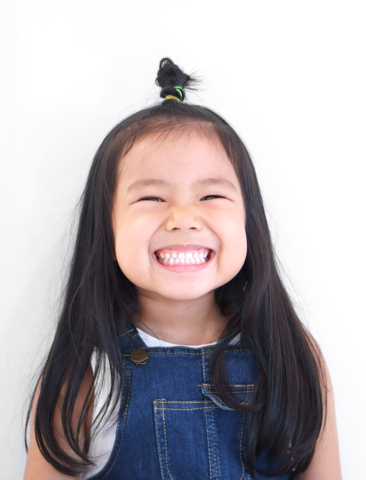 Asian children cute or kid girl and kindergarten student happy smile white teeth and laugh with wear dungarees jean for fashion on white background with space isolated