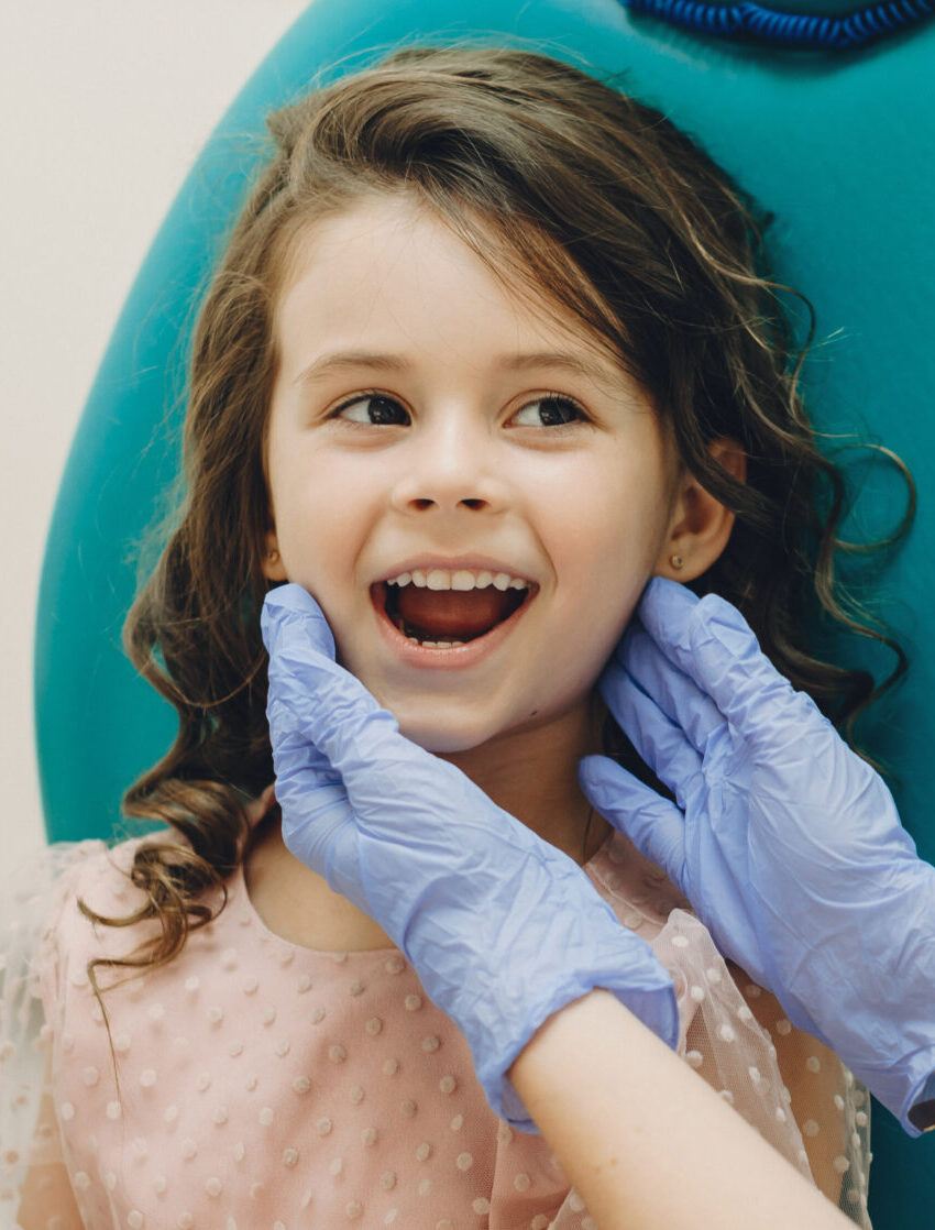 Portrait of a cute little girl showing her teeth to her pediatri stomatologist before doing a teeth surgery.