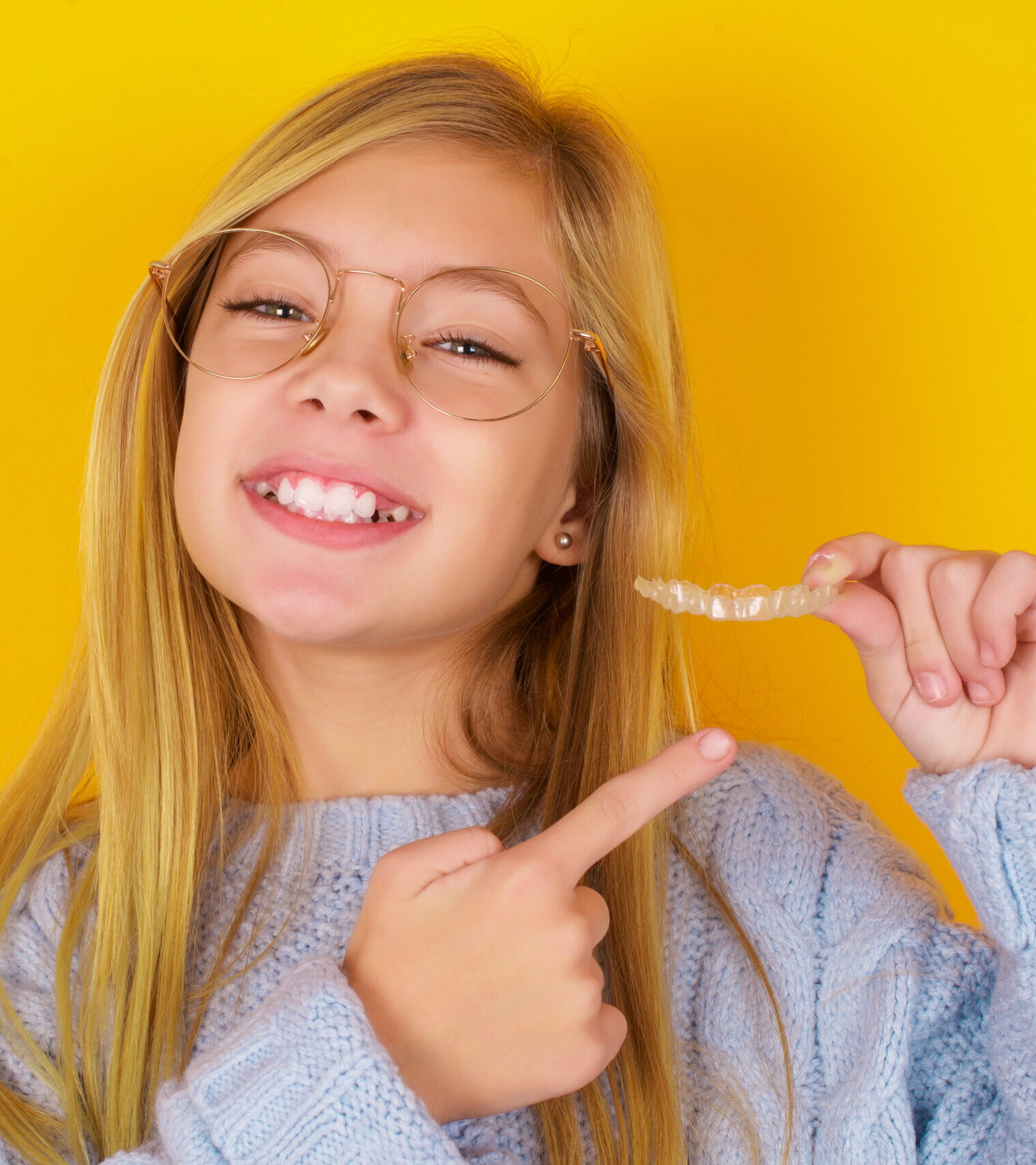 MODEL holding an invisible aligner and pointing at it. Dental healthcare and confidence concept.