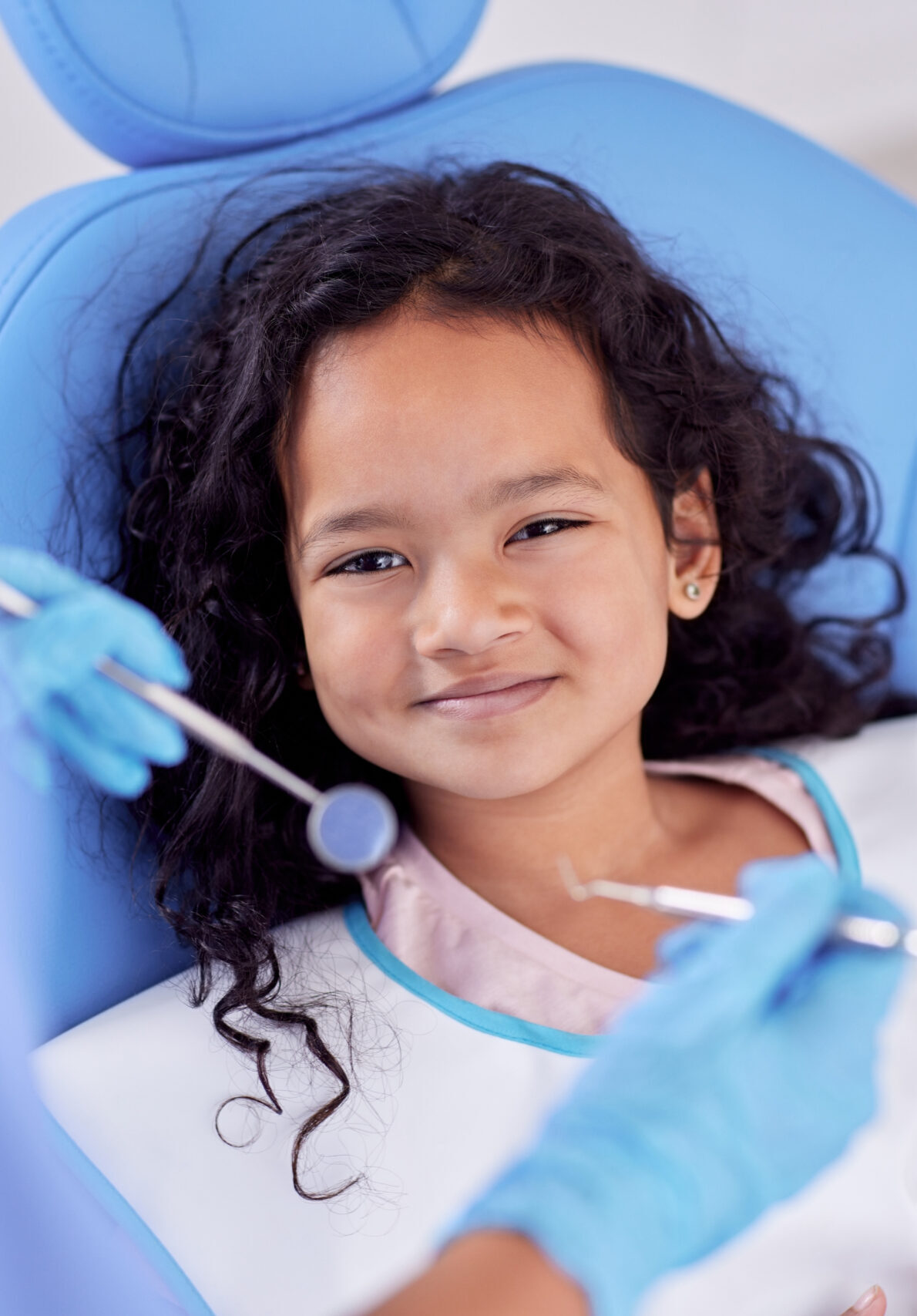 Dentistry, portrait and girl child at the dentist for teeth cleaning, oral checkup or consultation. Healthcare, smile and kid laying on the chair for dental mouth examination with equipment in clinic.