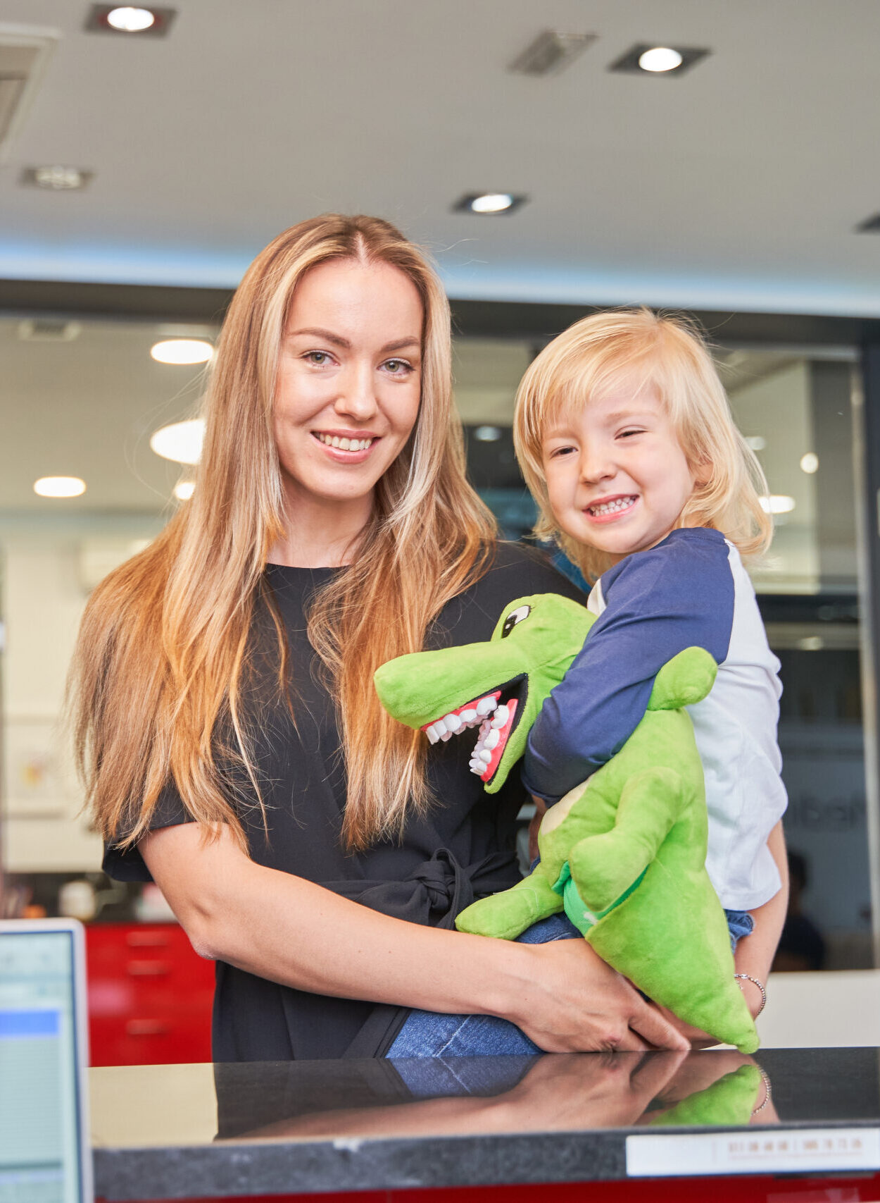 mother holds her child in her arms at the dentist's reception desk