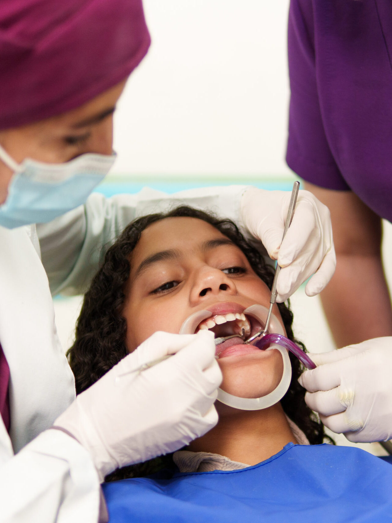 Dentist and assistant examining a young patient's teeth in a dental clinic with a mouth retractor