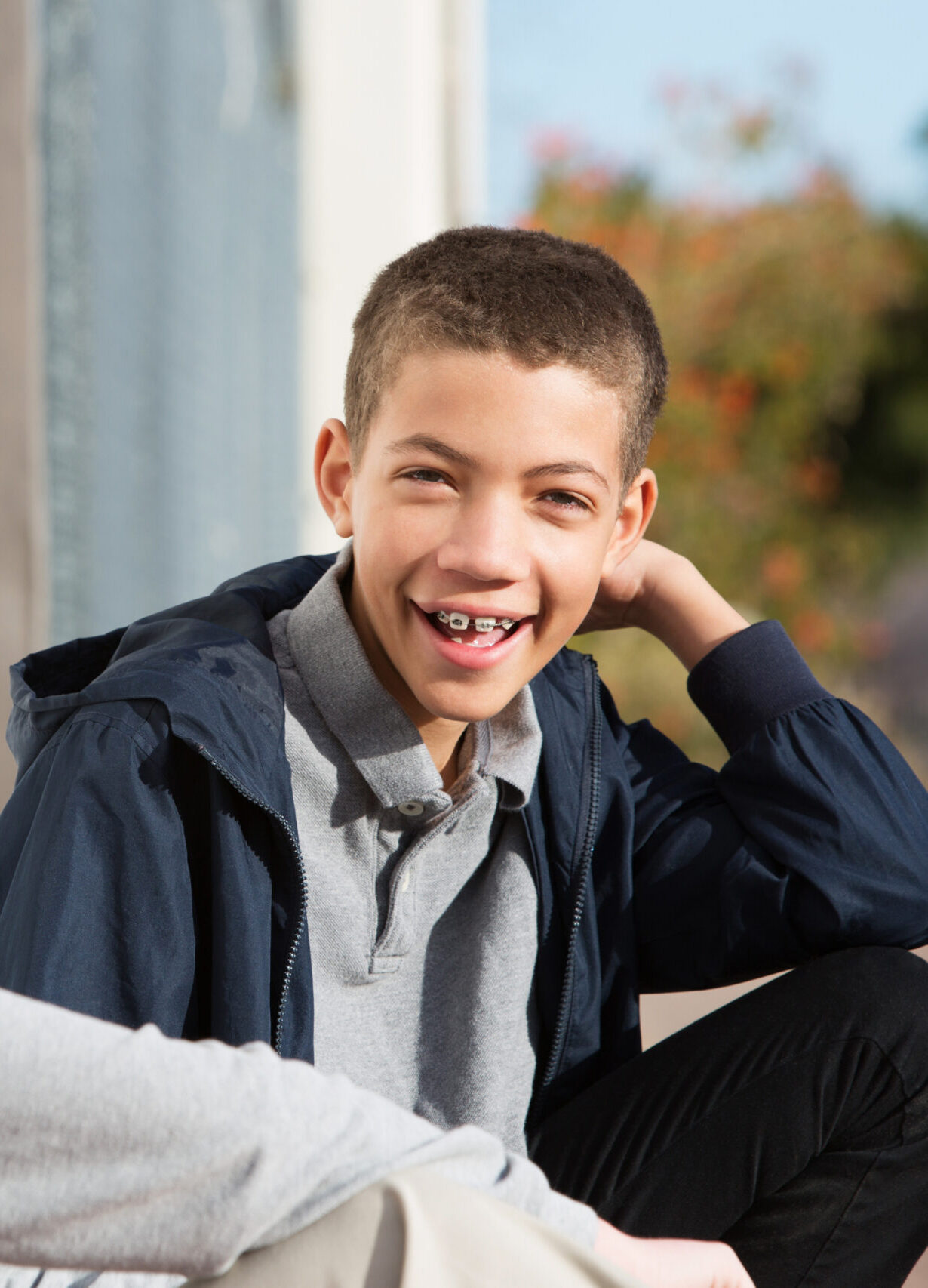 Laughing African American teen with braces sitting outside with blond friend