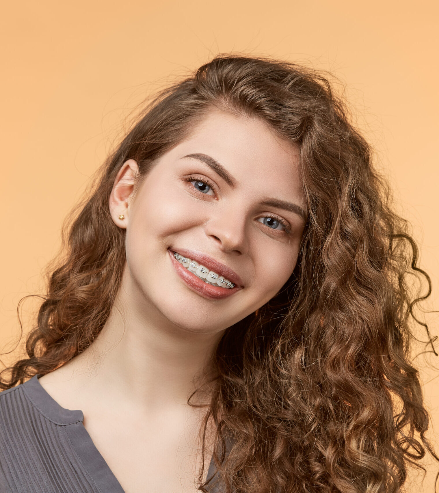 curly hair woman with brackets on biege background