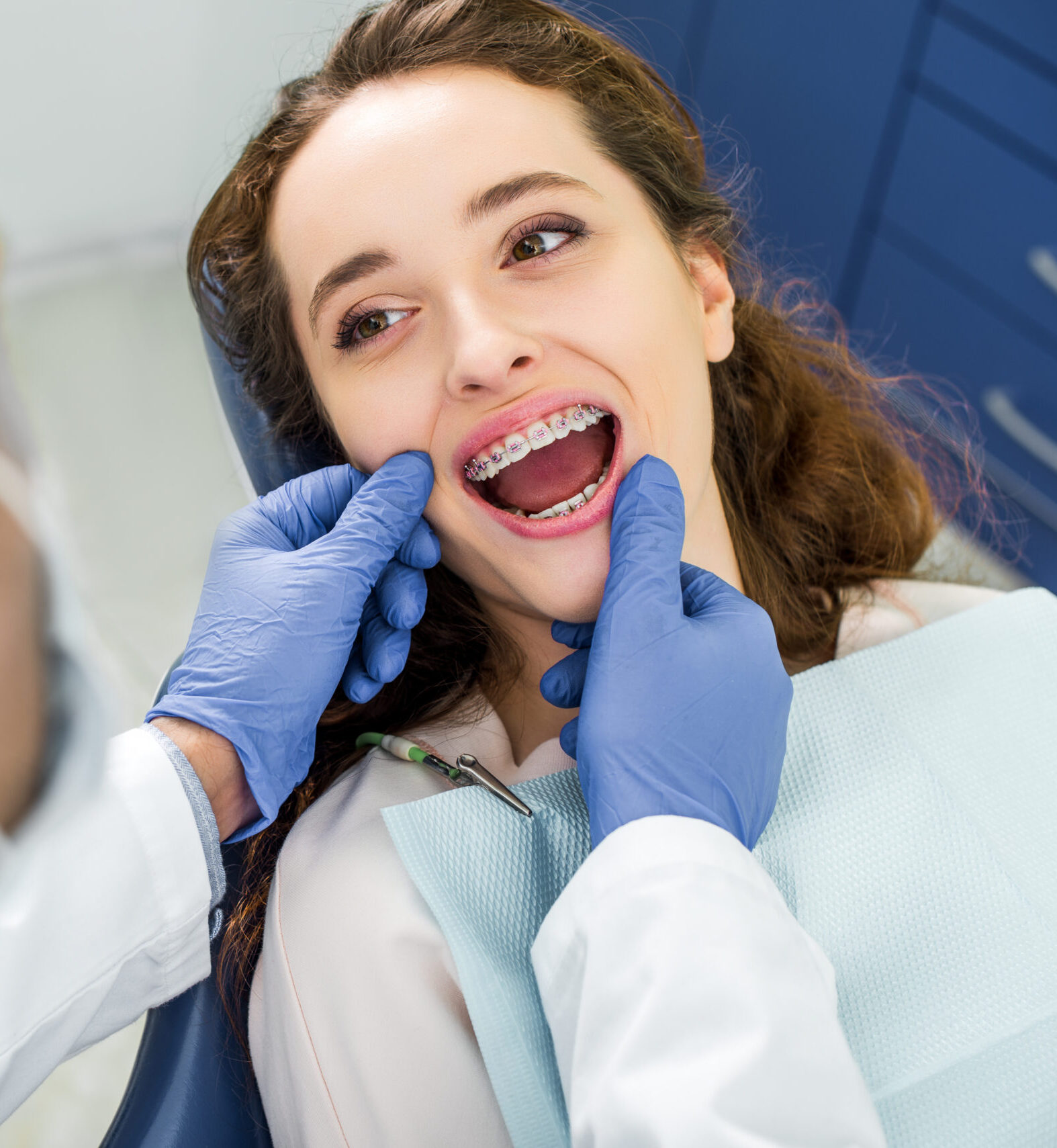 selective focus of woman in braces opening mouth during examination of teeth near dentist