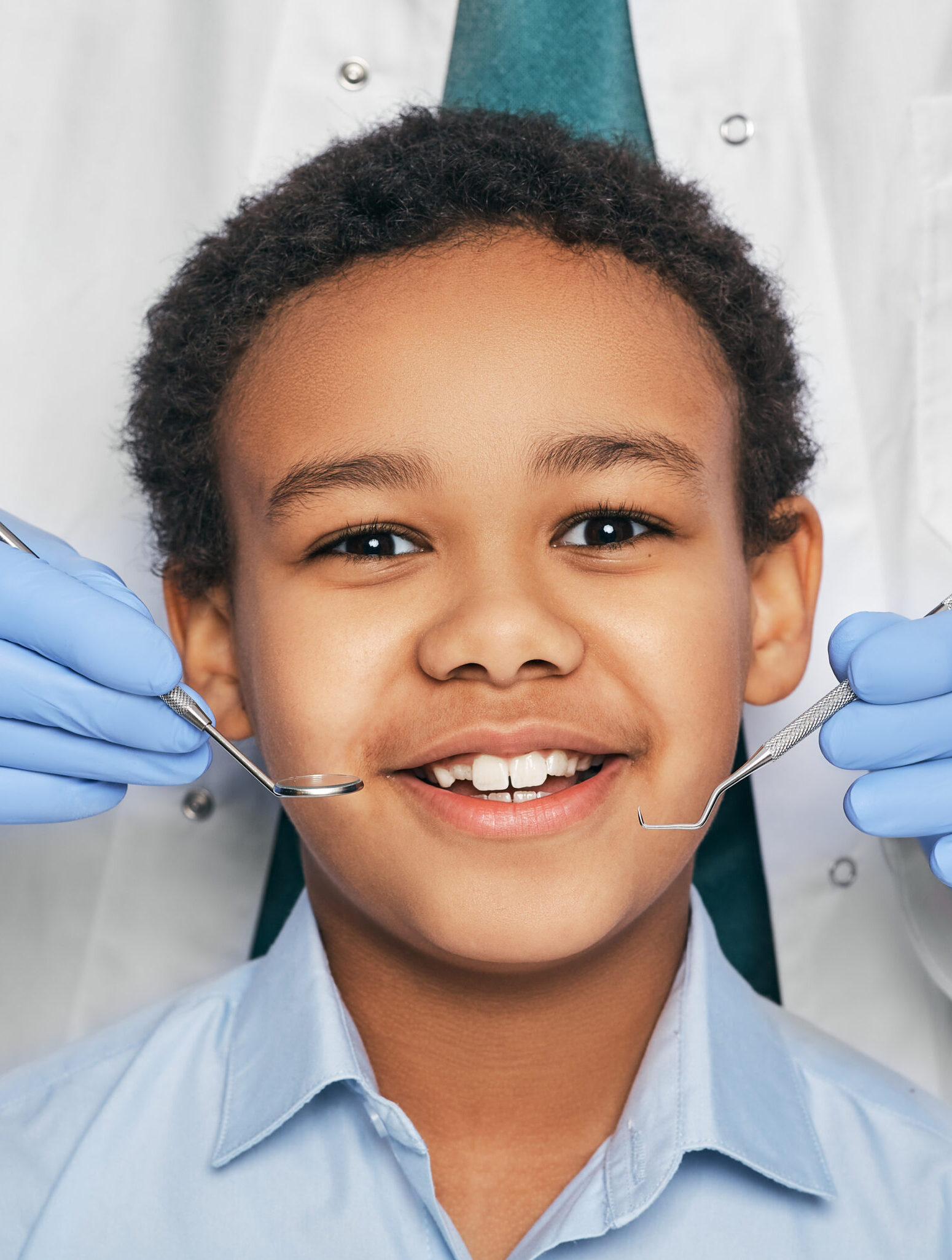 African American boy in dental clinic for children. Child with toothy smile during inspection of oral cavity by a dentist. Close-up