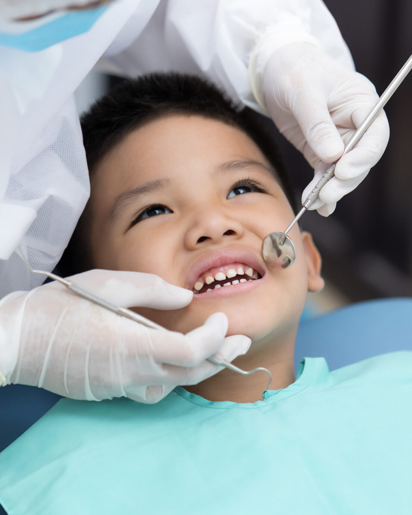 Dentist examining Asian little boy teeth in clinic.