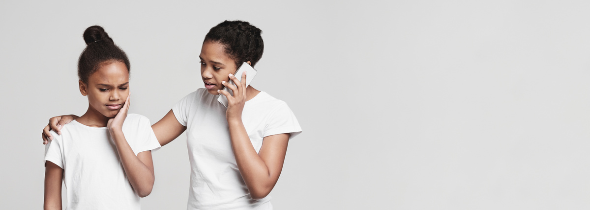 Little black girl suffering from tooth pain on grey background